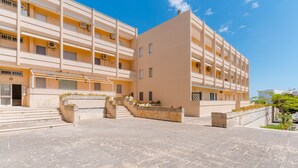 Un edificio de varios pisos con balcones, un patio central y una escalera que lleva a la entrada.