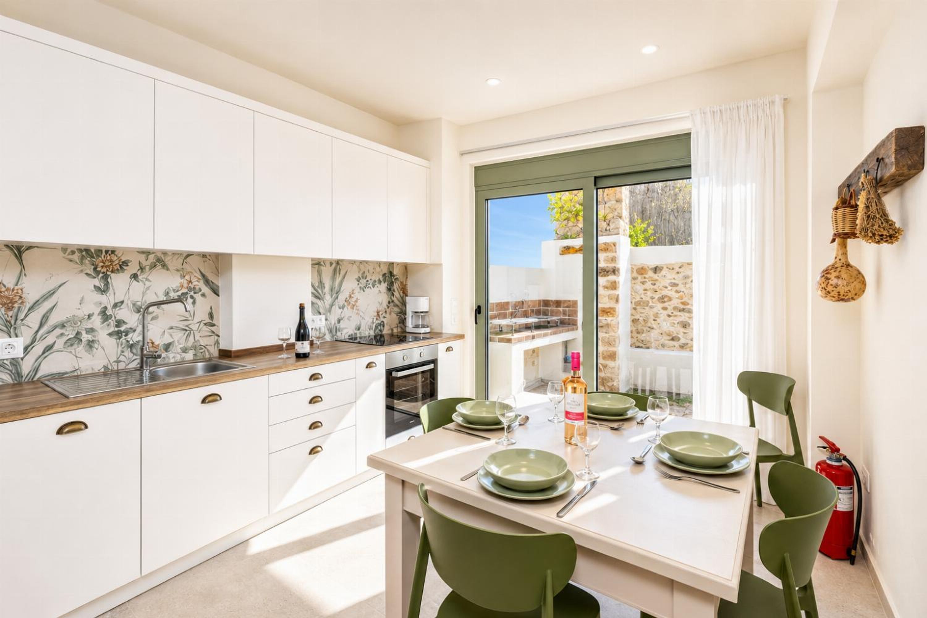 A modern kitchen with white cabinets, a marble backsplash, and a dining area with a table set for two.