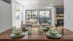 Un coin repas avec une table en bois dressée pour quatre personnes, un canapé et une cheminée.