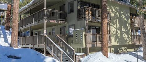 A multi-story building with balconies, a staircase, and a snow-covered ground.