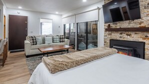 Un salon moderne avec un canapé, une table basse, une cheminée et un téléviseur fixé au mur.