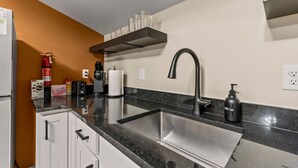 A modern kitchen with a stainless steel sink, a coffee maker, and a fire extinguisher.