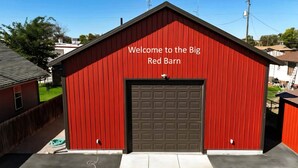 A red barn with a garage door, surrounded by residential buildings.
