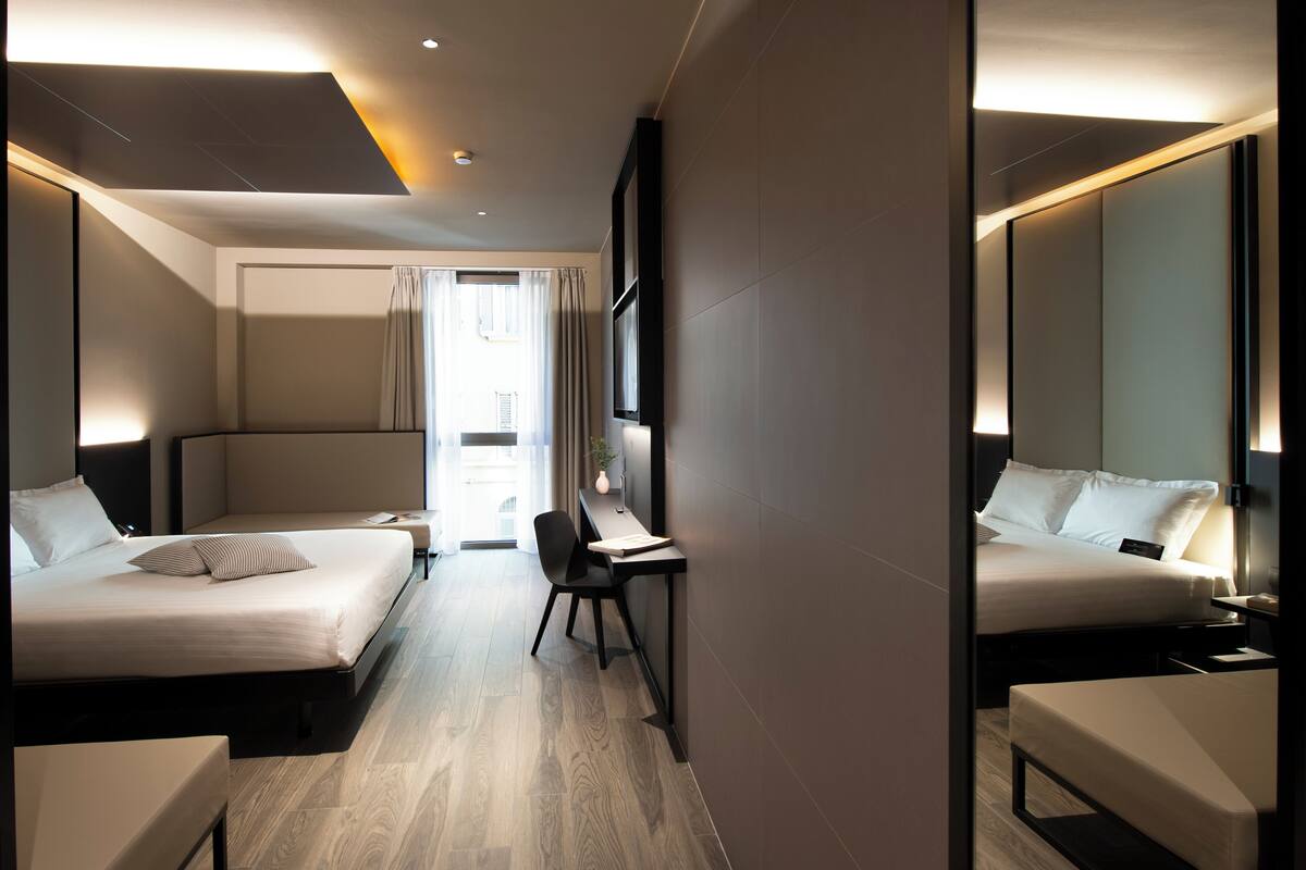 A hotel room with two beds, a desk, and a chair.