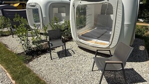 Two portable camping tents with attached chairs and a small table, set on a gravel surface with grass edging. - Directly on Lake Wallersee - Cubes - SELF CHECK-IN (Henndorf am Wallersee)