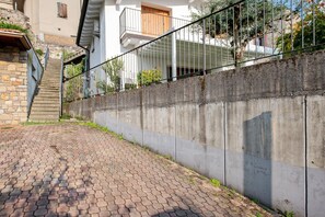 Asfaltoitu polku johtaa rakennukseen, jossa on betoniseinä, metallikaide ja portaikko.
