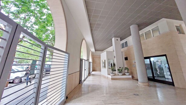 A spacious corridor with high ceilings, large columns, and a view of the outdoors. - 4BNB - Porta Portese Cozy Apartment (Rome)