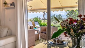 Una habitación con sofá, muebles de mimbre, una mesa de comedor y vistas al exterior.