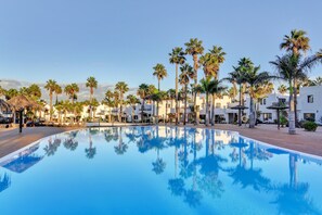 A swimming pool reflecting palm trees and white buildings. - Vacaciones 'Loleta' with Pool, Slides, Private Terrace and Wi-Fi (Corralejo)