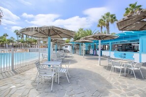 A poolside area with outdoor seating, umbrellas, and a bar.