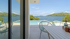 A balcony with a pool, two chairs, and a table with a bottle and jar. - Villa Pantone - Three Bedroom Villa, Sleeps 6 (Le Robert)