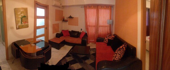 A living room with a sofa, a coffee table, and a painting on the wall.
