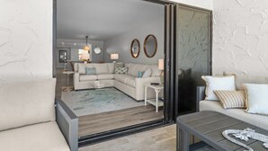 A modern living room with a sofa, coffee table, and a glass door leading to another room.