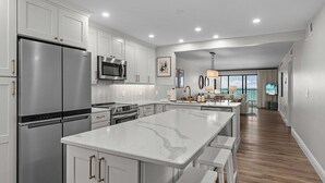 A modern kitchen with stainless steel appliances, a large island, and a dining area with a view.