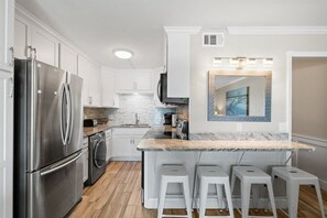 A modern kitchen with stainless steel appliances, white cabinetry, and a marble countertop. - 1bd 1.5ba 3rd Floor Summit Beach Front Sleeps 5 (Panama City Beach)