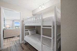 Une chambre avec un lit superposé, un canapé et une fenêtre avec des rideaux.