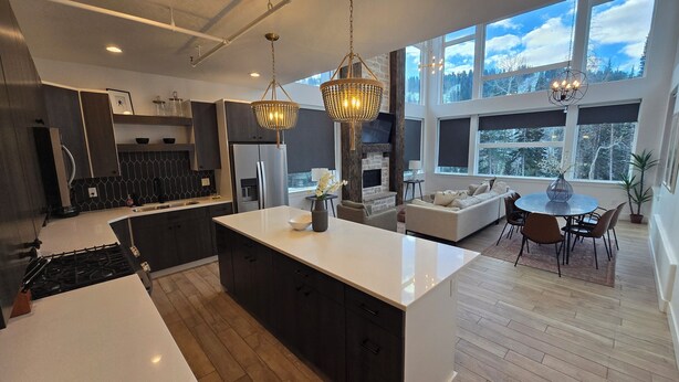 A modern kitchen with a central island, a dining area with a round table, and a cozy seating area with a fireplace. - Eagle Point Resort (Beaver)