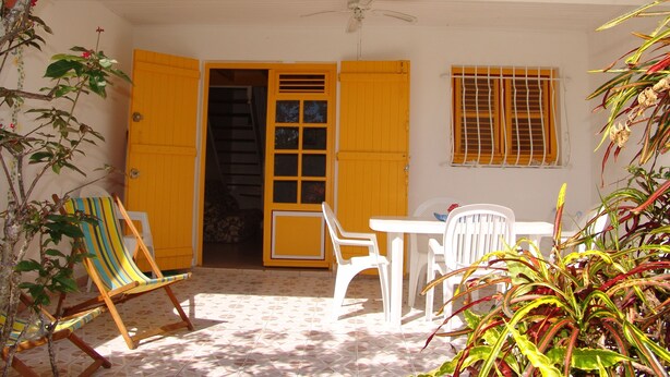 A house with a tiled roof, a white exterior, and a porch with a table and chairs. - AN ANVI, vacation home 400m from the sea (Sainte-Anne)