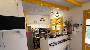 A kitchen with a central island, yellow and white walls, and a tiled floor. - AN ANVI, vacation home 400m from the sea (Sainte-Anne)