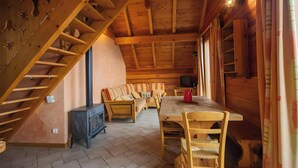 Un intérieur en bois comprenant un escalier, un ensemble de canapés, une table et un téléviseur.