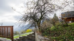 Un escalier en pierre mène à un bâtiment entouré d’une clôture en bois et à côté duquel se trouve un arbre aux feuilles vertes.