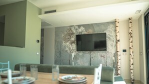 A dining area with a wooden table, chairs, and a television mounted on the wall. - Il Piccolo Paradiso - Acero - by Be Your Home (Civitavecchia)