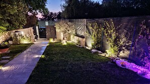A well-maintained garden with a paved walkway, a lawn, and various plants. - Il Piccolo Paradiso - Acero - by Be Your Home (Civitavecchia)