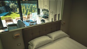A bedroom with a bed, a view of the garden, and a kitchenette. - Il Piccolo Paradiso - Acero - by Be Your Home (Civitavecchia)