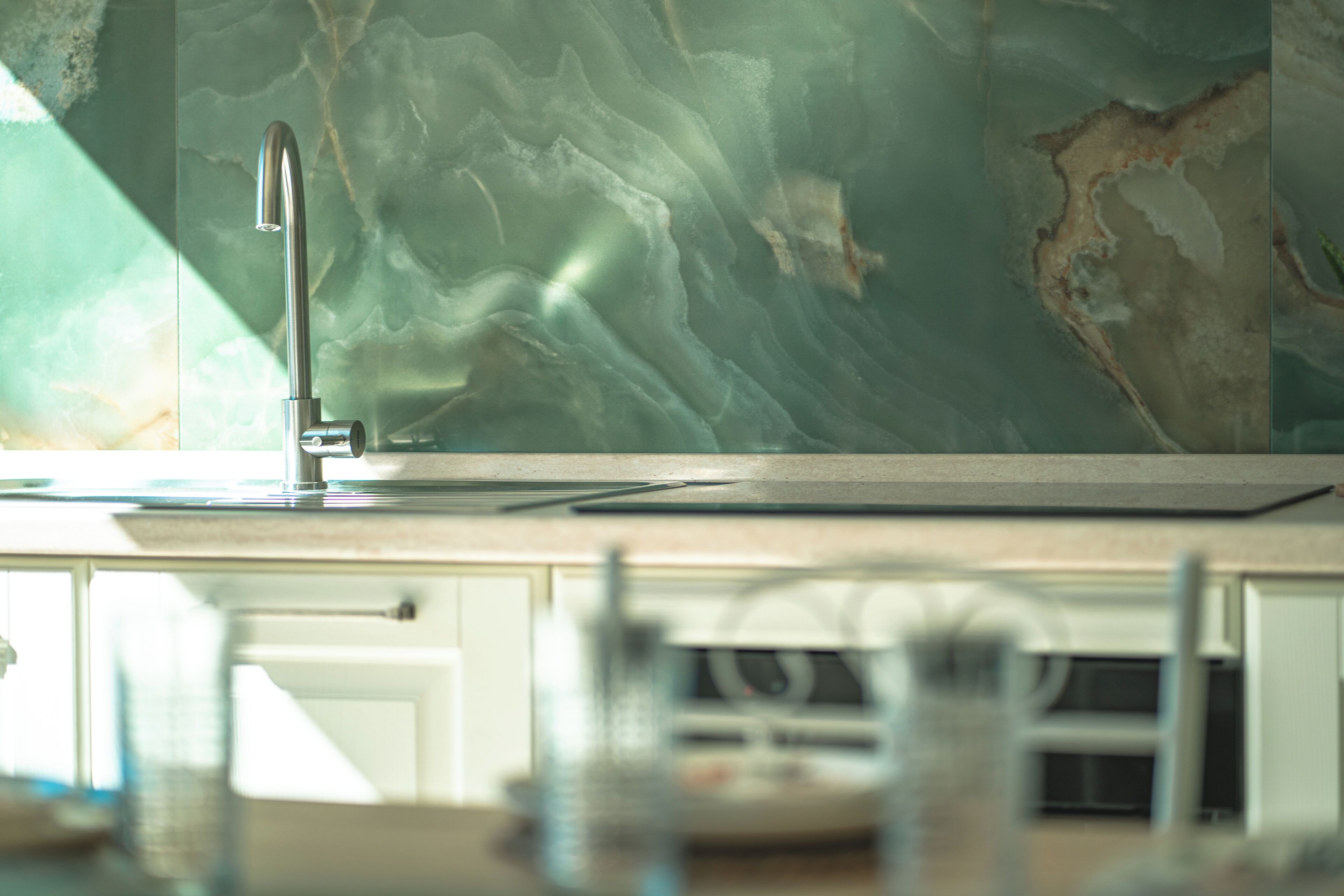 A kitchen with a modern faucet and a marble backsplash.