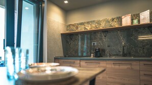 A modern kitchen with marble countertops, wooden cabinets, and a built-in coffee maker. - Il Piccolo Paradiso - Magnolia - by Be Your Home (Civitavecchia)