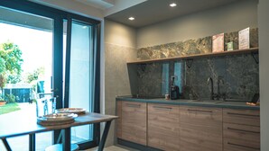 A modern kitchen with wooden cabinets, a marble backsplash, and a large window. - Il Piccolo Paradiso - Magnolia - by Be Your Home (Civitavecchia)