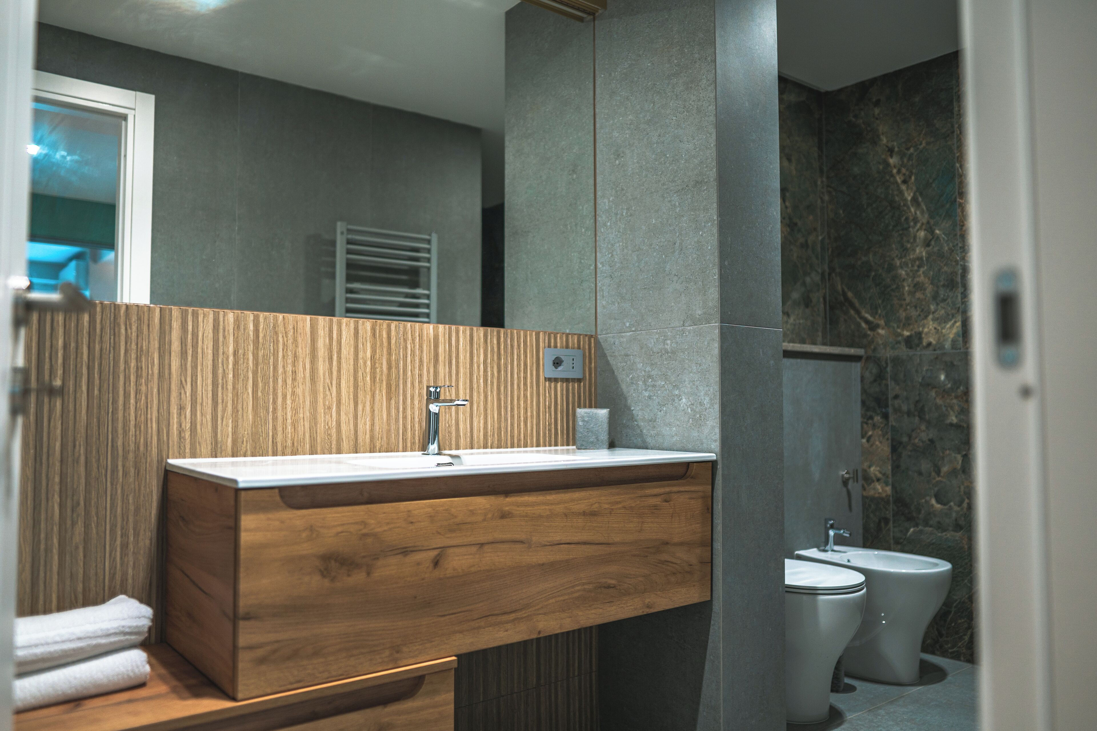 Un baño moderno con tocador de madera, lavamanos y retrete.