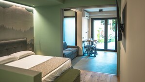 A bedroom with a bed, a sofa, a dining table with chairs, and a view of the outside. - Il Piccolo Paradiso - Magnolia - by Be Your Home (Civitavecchia)