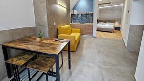 Een kleine hotelkamer met een eethoek, een bed en een badkamer.