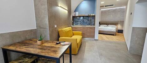 Ein kompaktes Hotelzimmer mit Essbereich, einem Bett und einem Badezimmer.