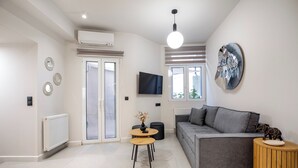 Una sala de estar moderna con un sofá gris, una mesa de centro redonda y un televisor de pantalla plana montado en la pared.