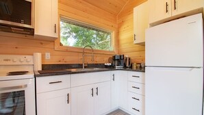 Eine moderne Küche mit weißen Schränken, einer Edelstahl-Dunstabzugshaube, einem Backofen, einem Spülbecken mit Armatur und einem Kühlschrank.