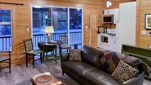 Ein gemütliches Blockhaus-Interieur mit Ledersofa, Holzesstisch und Küchenzeile.