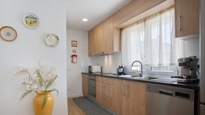 Una cocina moderna con armarios de madera, un refrigerador de acero inoxidable, un microondas y una cafetera.