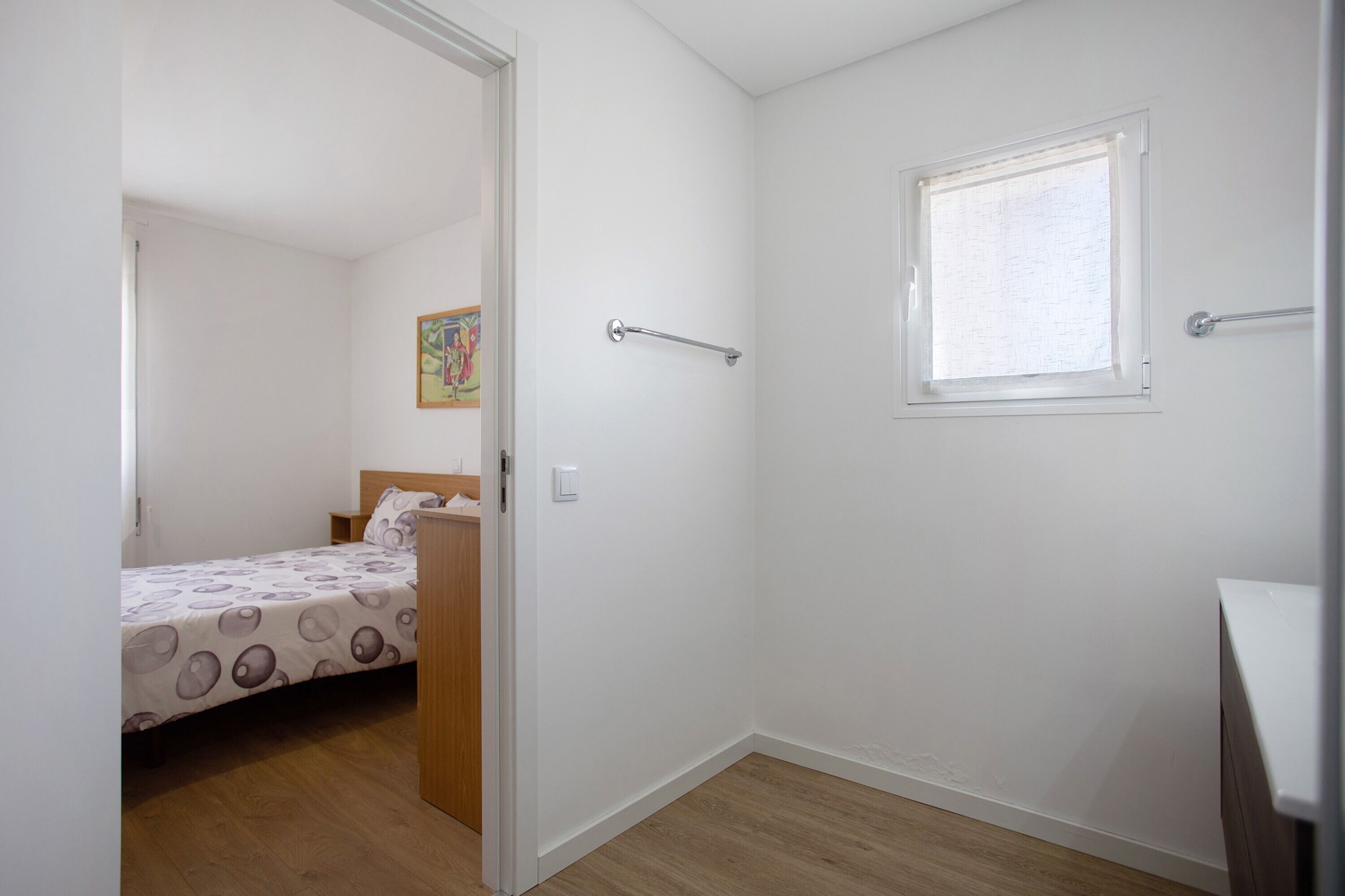 Une chambre à coucher avec un lit, une fenêtre et une porte donnant sur une autre pièce.
