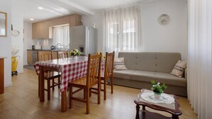 Un comedor con una mesa dispuesta para cuatro personas, un sofá y una cocina al fondo.