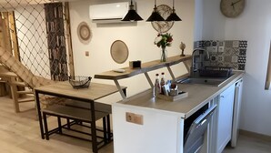 Una cocina moderna con una isla de madera, lámparas colgantes negras, un reloj y un panel decorativo en la pared.
