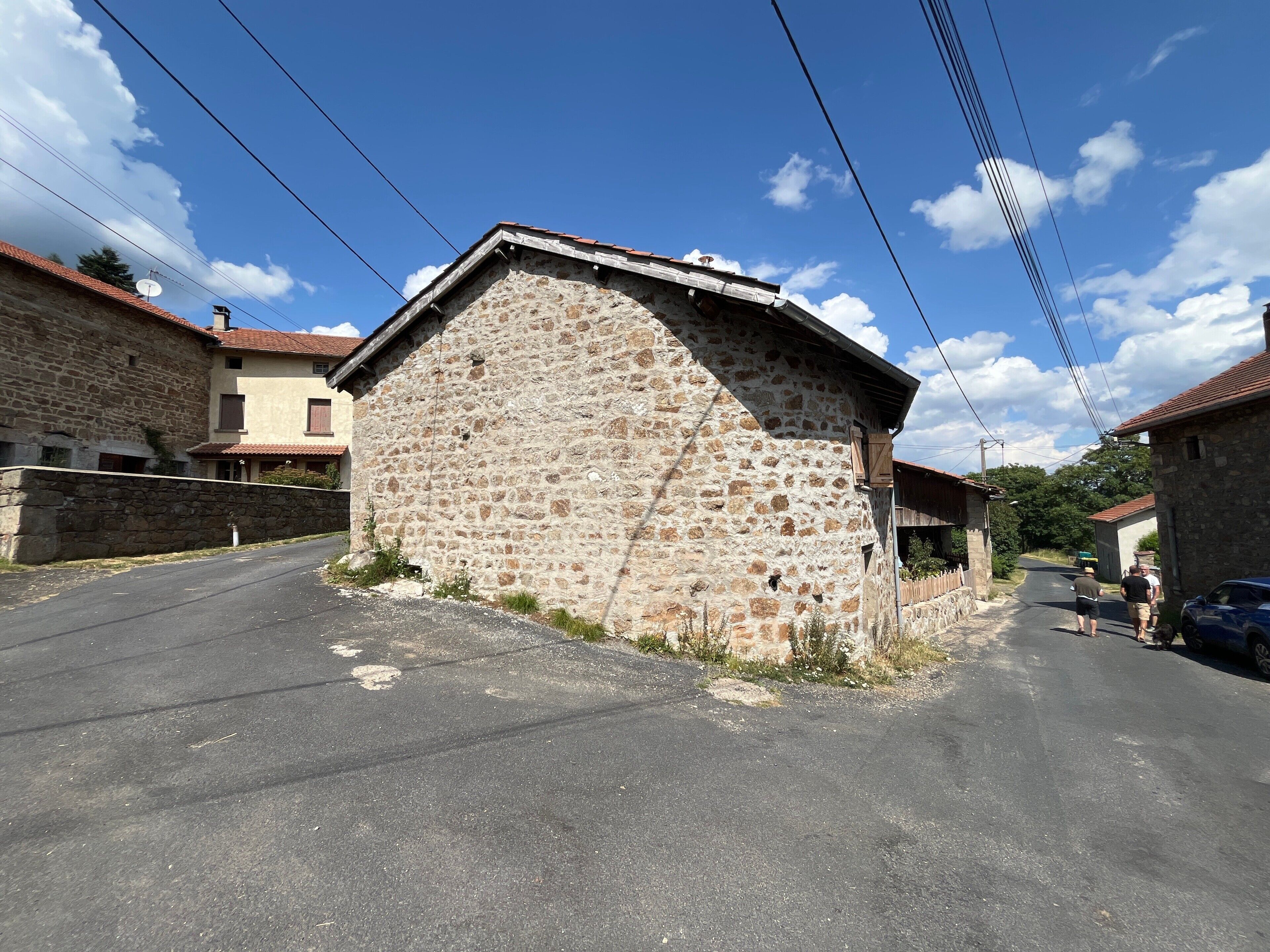 Un edificio in pietra con tetto spiovente, una strada lastricata e un cielo sereno.