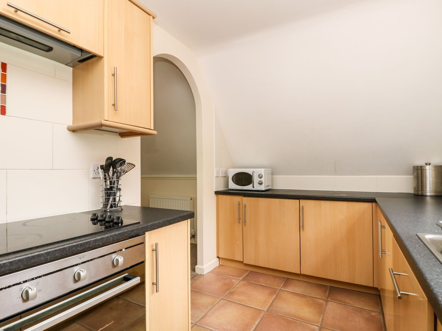 A kitchen with wooden cabinets, a black countertop, a microwave, and a gas stove.