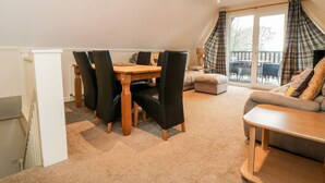 A cozy living room with a wooden dining table, black chairs, a beige sofa, and a small wooden coffee table. - Valley Lodge 31 (Gunnislake)