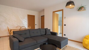 A modern living room with a sectional sofa, a small round table, and a yellow bean bag.