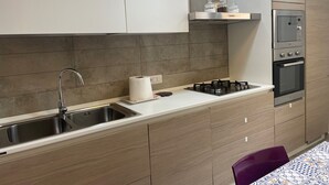 A modern kitchen with a stainless steel sink, a gas stove, a built-in oven, and a microwave.