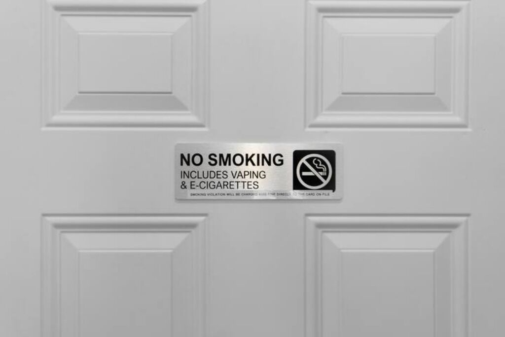 A door with a 'NO SMOKING' sign that includes vaping and e-cigarettes.