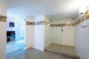 Une salle de bain moderne avec une douche à parois de verre, des murs recouverts de carreaux blancs et une bordure décorative.