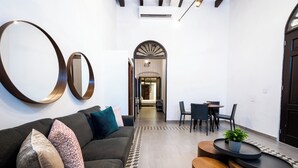 A modern interior with a sofa, a coffee table, and a dining area with chairs and a table. - 153 Luna by Stay with Bear (San Juan)